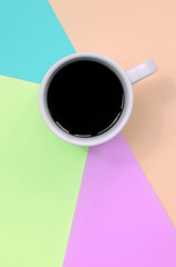 Small white coffee cup on texture background of fashion pastel pink, blue, coral and lime colors...