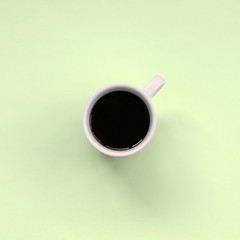 Small white coffee cup on texture background of fashion pastel lime color paper