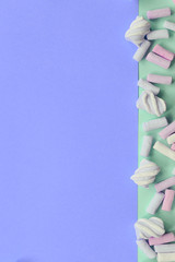 Colorful marshmallow laid out on green and lilac paper background