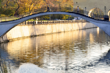 Fototapeta premium Autumn. View of the bridge over the river in the city on which the man and the woman parted