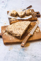 Vegan chocolate cake stuffed with oats and coconut flakes on parchment paper and wooden board. Sweet healthy diet dessert. Vegetarian food.