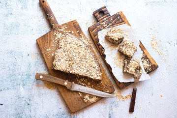 Chocolate cake stuffed with oats and coconut flakes on parchment paper and wooden board. Sweet healthy diet dessert. Vegetarian food.