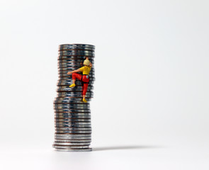 A miniature woman climbing a pile of coins. The concept of infinite competition society.