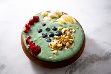 Spirulina yogurt with fruit in wooden bowl