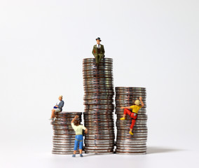 Piles of coins and miniature people. The concept of competition and wealth gap.