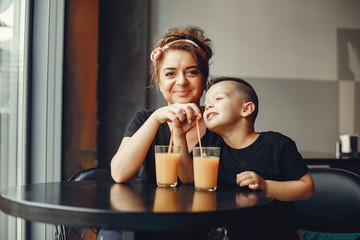 Family in a cafe. Mother in a black t-shirt. Cute little boy drinking a juice