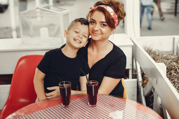Family in a cafe. Mother in a black t-shirt. Cute little boy drinking a juice
