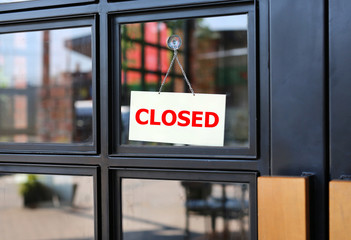 Closed sign board hanging on door of cafe.