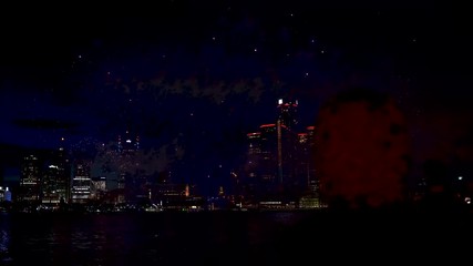 Fireworks going off over the Detroit river with a male on looker in the foreground.