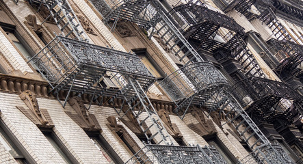 Naklejka premium Facades of historic buildings in the Soho district of New York. The characteristic iron safety stairs on the facades