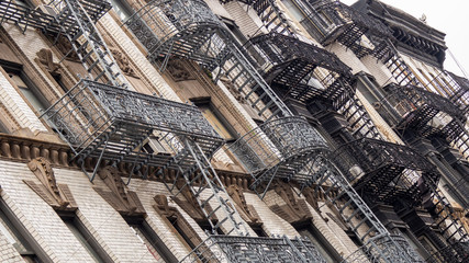 Naklejka premium Facades of historic buildings in the Soho district of New York. The characteristic iron safety stairs on the facades