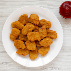 Chicken nuggets and ketchup on a white wooden surface. Overhead, from above, flat lay. Close-up.
