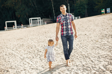 Family playing on the sand. Father in a t-shirt. Cute little girl