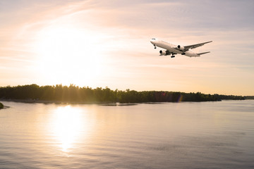 Airliner over the river. Sunset in the evening.