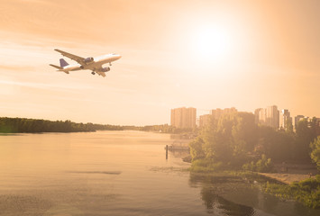 The plane over the river and the city. The evening sunset.