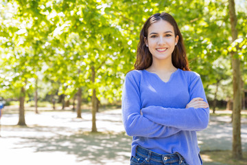 Fototapeta premium Smiling confident girl protecting nature. Eco volunteer standing in city park and looking at camera. Environment concept