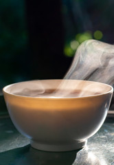 White bowl of hot soup with smoke served on metal tray for breakfast.