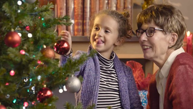 Little girl decorating a Christmas tree with her grandmother