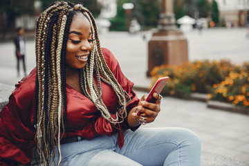 Cute black woman have fun in a city. Beautiful black girl in a red blouse