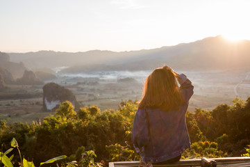 Young woman watching sunrise high in the mountain at Phu Lung ka,Thailand