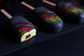 Sliced pistachio ice cream with raspberry insertion and dark chocolate glaze and decorations