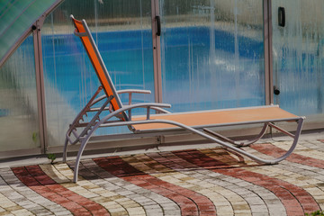 Modern chaise longue stands in front of outdoor indoor pool