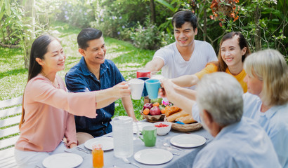 Mix aged big family enjoy having outdoor party eating food at backyard home, warm and happy lifestyle family concept
