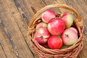 Red apples in wicker basket on wooden boards
