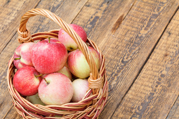 Red apples in wicker basket on wooden boards