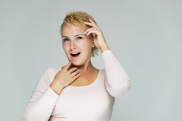 Photo portrait of a beautiful girl blonde woman with short curly hair on a white background talking and showing a lot of emotions. An experienced model shows hands. Beauty.