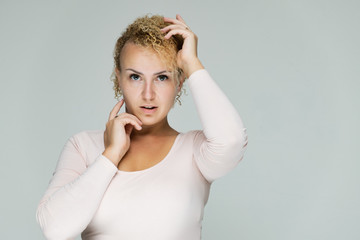 Photo portrait of a beautiful girl blonde woman with short curly hair on a white background talking and showing a lot of emotions. An experienced model shows hands. Beauty.