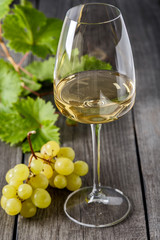White wine in a glass and a bunch of grapes