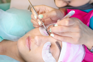 Woman master in the beauty salon is working on eyelash extension to the client. Industry and professions in the field of beauty
