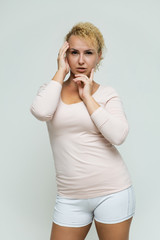 Photo portrait above the knee of a beautiful blonde woman girl with short curly hair on a white background in bright lingerie talking and showing a lot of emotions. An experienced model shows hands.