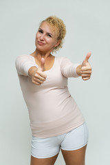 Photo portrait above the knee of a beautiful blonde woman girl with short curly hair on a white background in bright lingerie talking and showing a lot of emotions. An experienced model shows hands.