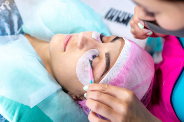 Woman master in the beauty salon work on eyelash extension to the client. Process of working as a professional stylist for lengthening eyelashes