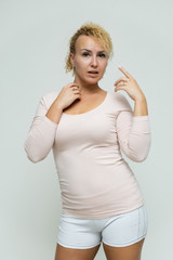 Photo portrait above the knee of a beautiful blonde woman girl with short curly hair on a white background in bright lingerie talking and showing a lot of emotions. An experienced model shows hands.