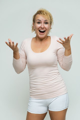 Photo portrait above the knee of a beautiful blonde woman girl with short curly hair on a white background in bright lingerie talking and showing a lot of emotions. An experienced model shows hands.