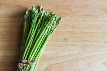 Bunch of fresh raw garden asparagus on wooden table background.