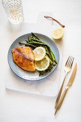 Roasted tilapia fish with asparagus on a ceramic plate. Healthy mediterranean diet lunch or dinner. Top view, flat lay.