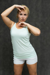 Photo portrait above the knee of a beautiful girl blonde woman with short curly hair on a gray background in bright linen is talking and showing a lot of emotions. An experienced model shows hands.