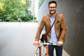 Fototapeta na wymiar Happy young stylish businessman going to work by bike
