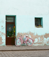 Fototapeta na wymiar Old pink bicycle leaning against a green damaged wall