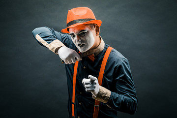 clown and Halloween theme: crazy clown with knife in hand isolated on dark background in Studio.