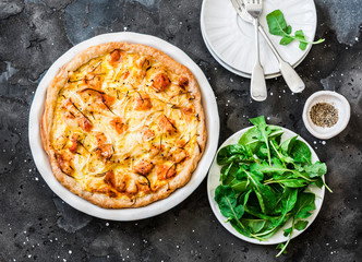 Smoked trout, potatoes, leek pie on dark background, top view