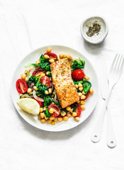 Warm chickpeas, cherry tomatoes, spinach salad and baked salmon - healthy lunch on a light background, top view