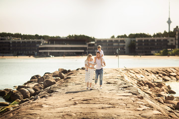 A young family, father, mother and two children is walking along the sea pier on the beach in Estonia, Tallinn