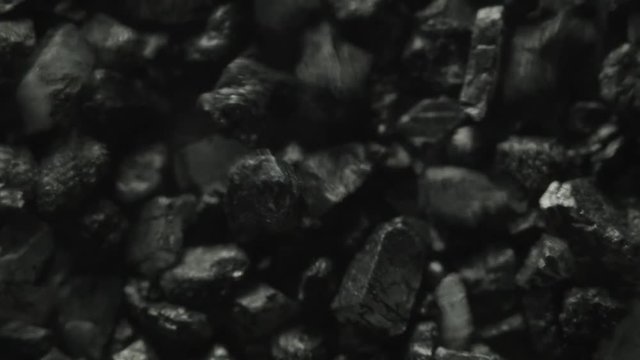 Extreme macro of black stones moving through vibrations of sound.