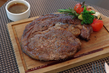 Grilled steak with broccoli, rosemary, small tomato and asparagus on wood plate