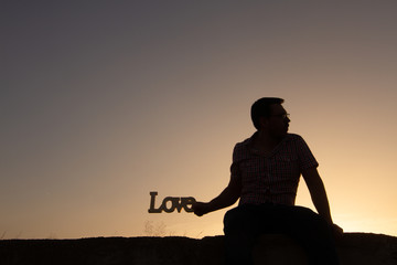 silhouette of man with poster that puts love